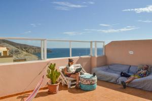 two people sitting on a balcony with a view of the ocean at Aloe Vera Shared House in El Médano