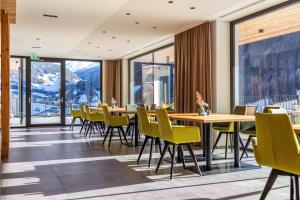 uma sala de jantar com mesas e cadeiras e janelas grandes em Stoana Apt 3-5 em San Giacomo