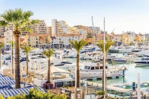 een jachthaven met boten, palmbomen en gebouwen bij Villa Cavaco in Vilamoura