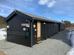 a black building with a row of stalls at Rett ved Raudalen Alpinanlegg in Beitostøl