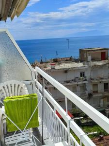 einen Balkon mit einem grünen Tisch, Stühlen und Meerblick in der Unterkunft Niki Breeze cozy apartment in Nea Kallikratia