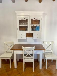 einem Esstisch mit 2 Stühlen und einem weißen Schrank in der Unterkunft Casa Juan Harina in Setenil de las Bodegas