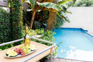 a table with a bottle of wine and fruit next to a swimming pool at Garden Oasis 1 Villa With Private Pool in Four Roads