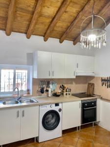 eine Küche mit weißen Schränken, einer Spüle und einem Geschirrspüler in der Unterkunft Casa Juan Harina in Setenil de las Bodegas
