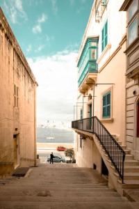 a person walking down an alley between two buildings at Chic, Stylish & Spacious flat in central Valletta in Valletta