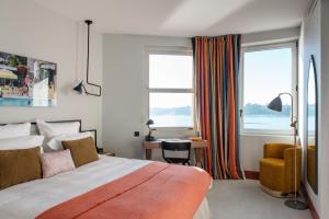 a bedroom with a bed and a desk and two windows at Castelbrac Hotel & Spa in Dinard