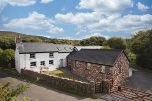 an exterior view of a house with a stone wall at Lower Mill - 3 Bedroom - 5* Retreat - Llangennith in Llangennith