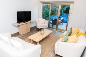 uma sala de estar com dois sofás brancos e uma televisão em Garden Oasis 1 Villa With Private Pool em Four Roads