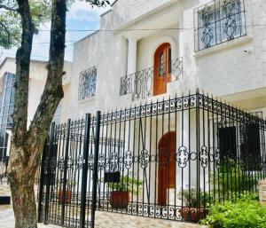 a white house with a black wrought iron fence at The Place Hotel Boutique in Cali