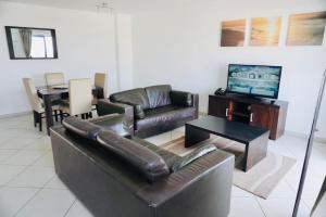 sala de estar con sofá de cuero y TV en Residência Oceaníca Meliá Dunas Beach Resort & Spa, en Santa Maria