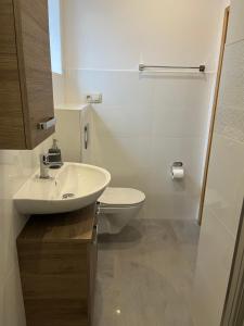 Pokój z kuchnią u Lennoxa 2 في بوك: حمام ابيض مع مرحاض ومغسلة