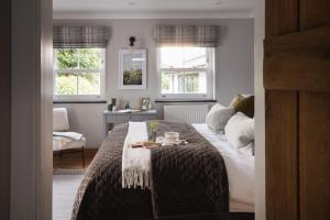 a bedroom with a bed with a table and two windows at Lower Mill - 3 Bedroom - 5* Retreat - Llangennith in Swansea