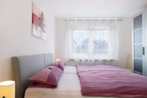 Bodensee Apartment Gresser في ميكنبورن: غرفة نوم مع سرير وملاءات وردية ونافذة
