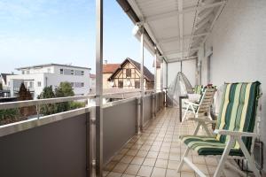 a balcony with chairs and a view of a building at Bodensee Apartment Gresser in Meckenbeuren