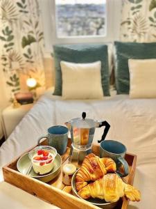 a tray of croissants and coffee on a bed at Le Cottage Breton, hypercentre historique StB in Saint-Brieuc