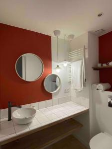 baño con lavabo y 2 espejos en la pared en LA SUITE D’AMOUR Cucuron : une maison de village. en Cucuron
