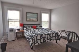 a bedroom with a black and white bed and windows at Housepitality - The Sail Away Townhouse in Columbus