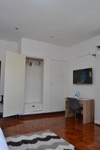 a living room with a desk and a white wall at Kutenga Guest House in Maputo