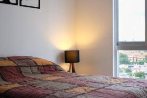 a bedroom with a bed with a lamp and a window at Escenia Comfort, 9th floor apt with awesome views! in Guadalajara