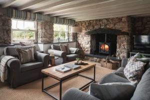 a living room with couches and a stone fireplace at Lower Mill - 3 Bedroom - 5* Retreat - Llangennith in Swansea