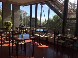 un restaurante con mesas, sillas y ventanas grandes en Yemanya Hostal, en Concón