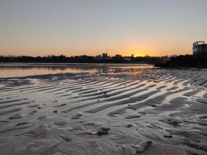 a beach with the sun setting in the background at English Point Residence Beach Apartments Mombasa in Mombasa