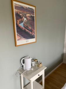 a small white table with a picture on the wall at Perssons i Backens Pensionat- Sjötorps Vandrarhem & Rum in Sjötorp