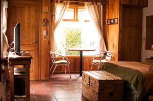 1 dormitorio con cama, mesa y ventana en Cabañas Aitue en San Martín de los Andes