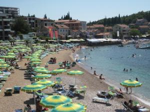 a beach with many umbrellas and people in the water at Apartments Danilo Kažanegra in Sveti Stefan