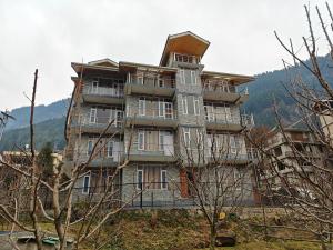 un grand bâtiment au sommet d'une colline plantée d'arbres dans l'établissement Aleo Villa, à Manali