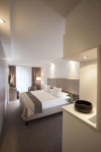 Schlafzimmer mit einem großen weißen Bett und einem Schreibtisch in der Unterkunft Hotel Erzgiesserei Europe in München