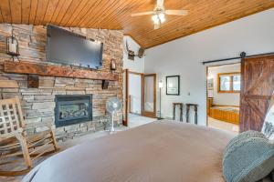 a bedroom with a fireplace and a tv on a stone wall at Rice Lake Cabin Retreat with Red Cedar Lake Access! in Rice Lake