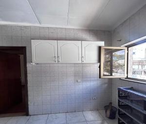 a kitchen with white cabinets and a tile wall at A Spacious 4BR 2 Bathroom Villa House @ Bole DT in Addis Ababa