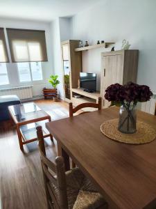 a living room with a wooden table with a vase of flowers at Apartamento Pena Furada in Ribadeo