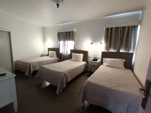 a hotel room with two beds and a window at Hotel Branco I in Praia da Vitória