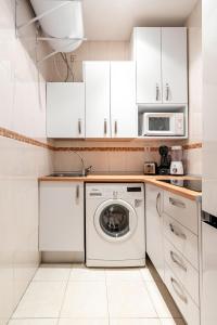 a white kitchen with a washing machine and a microwave at Atocha - Acogedor apartamento, centro de Madrid in Madrid