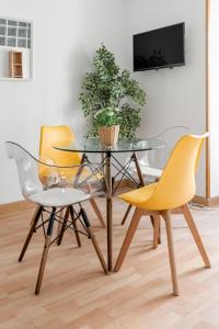 a dining room with a glass table and two yellow chairs at Atocha - Acogedor apartamento, centro de Madrid in Madrid