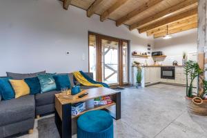 a living room with a couch and a table at Ostoja Lemany - domki na Kaszubach, sauna, balia-jacuzzi, plac zabaw, tyrolka , dwa boiska, miejsce na ognisko, grill gazowy in Lemany