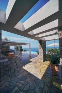 un patio con mesa, sillas y el océano en La Bella Villa, en Melínta