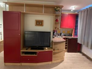 a kitchen with red cabinets and a flat screen tv at DIKOL Two-Room Apartment-SELF CHECK-in & FREE Parking Near City Center in Tallinn