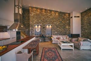cocina y sala de estar con pared de piedra en La Bella Villa, en Melínta