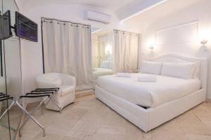 a white bedroom with a large white bed and a chair at Deluxe Suite Welness in Rome