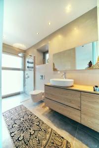 Un baño con lavabo, inodoro y espejo. en La Bella Villa, en Melínta