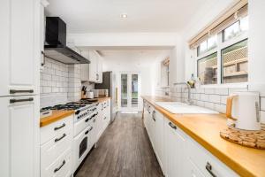 eine Küche mit weißen Geräten und einer hölzernen Arbeitsplatte in der Unterkunft Beautiful 3 bed Cottage Chorleywood. in Chorleywood