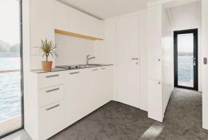 a white kitchen with a sink and a window at VIPliving Houseboat in Prague