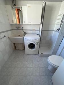 uma pequena casa de banho com uma máquina de lavar roupa e um WC em Yucca Apartment em San Vito lo Capo