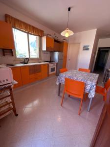 uma cozinha com uma mesa com cadeiras laranja e uma mesa e uma mesa em Yucca Apartment em San Vito lo Capo