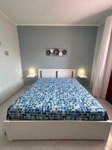 a bedroom with a bed with a blue and white comforter at Yucca Apartment in San Vito lo Capo