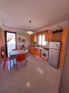 uma cozinha com uma mesa e um frigorífico branco em Yucca Apartment em San Vito lo Capo