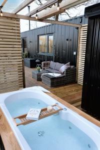 a jacuzzi tub on a patio with a couch at The Hideaways in Exeter